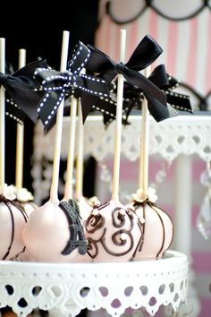 two cakes with candles on them sitting in front of a cake stand that is decorated with black and white ribbons