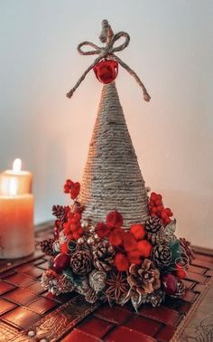 a christmas tree made out of wicker and pine cones with candles in the background