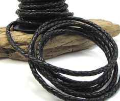 a black leather cord is on top of a piece of driftwood