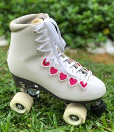 a pair of white roller skates with hearts on the front and side wheels in grass