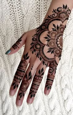 a woman's hand with henna tattoos on it