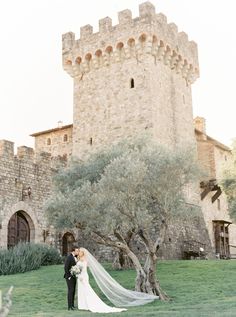 a bride and groom standing in front of a castle