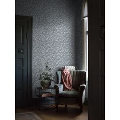 a chair sitting in front of a window next to a table with a potted plant on it