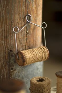 a spool of twine is hanging from a wooden post with a metal hook