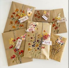 four envelopes with flowers on them and some tags attached to the front, sitting next to each other