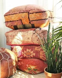 a pile of pillows sitting next to a potted plant