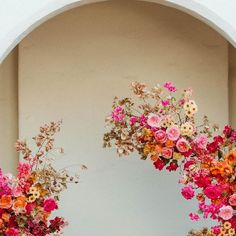 two vases filled with colorful flowers sitting on top of a white shelf next to a wall