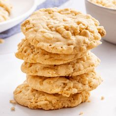 a stack of cookies sitting on top of a white table next to a bowl of oatmeal