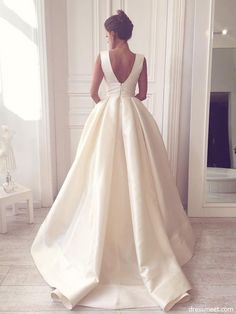 a woman in a white wedding dress looking at herself