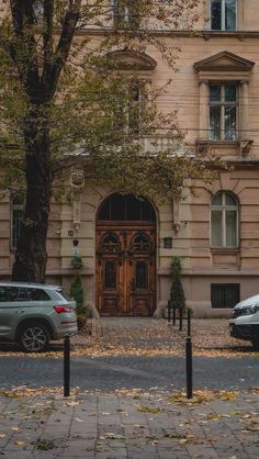 two cars parked in front of a building with a large wooden door and window on the side