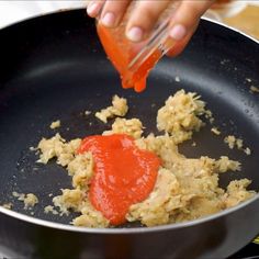 someone is adding ketchup to some food in a frying pan