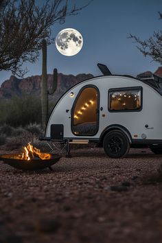 a camper parked in the desert with its door open next to a fire pit