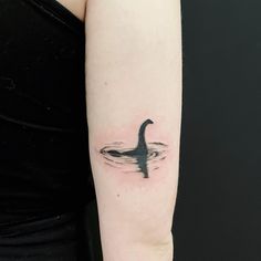 a woman's arm with a black and white tattoo of a duck in water