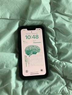 an iphone case sitting on top of a bed covered in white sheets and green sheets