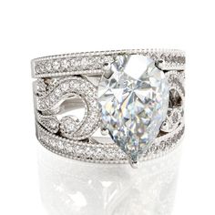 a white gold ring with a pear shaped diamond in the center and an intricate band around it