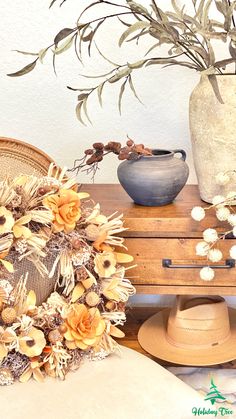 a table topped with a vase filled with flowers next to a hat and other items