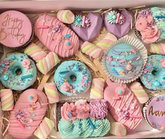 a box filled with lots of decorated donuts and cupcakes on top of each other