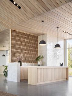 an open kitchen and living room area with wood paneling on the ceiling, large windows in the background