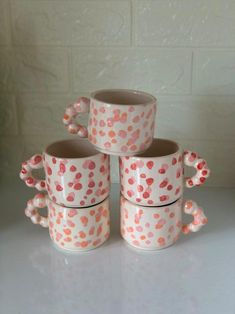 four coffee mugs stacked on top of each other with pink and orange polka dots