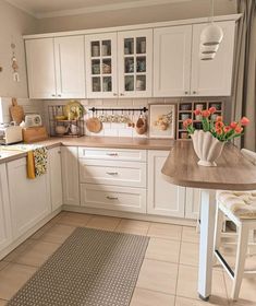 a kitchen with white cabinets and wooden counter tops is pictured in this image, there are flowers on the table