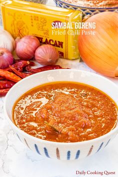 a bowl of soup sitting on top of a table next to onions and garlics