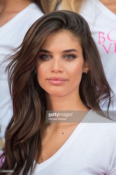 a close up of a person with long hair and wearing a white t - shirt