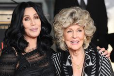 two women standing next to each other on a red carpet