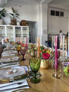 the table is set with candles, plates and flowers in vases on top of it