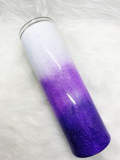 a purple and white cup sitting on top of a fur covered floor next to a can