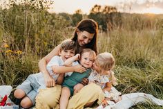 a woman sitting on top of a blanket with three children