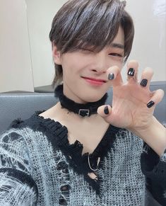 a woman with black nail polish holding her hand up to the camera while sitting down