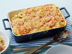 a casserole dish with cheese and tomatoes in it on a blue and white towel