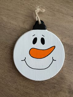 a wooden snowman ornament with an orange nose and black hat hanging from a string