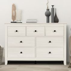 a white dresser sitting next to a lamp and vases on top of each other