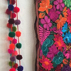 colorful flowers and pom - poms hanging on the wall next to each other