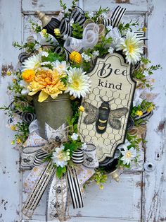 a bee kind wreath with flowers and ribbons on an old white door that says bee kind