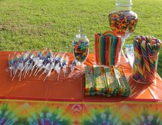 an assortment of candy and lollipops sitting on a table in the grass