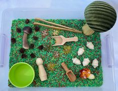 a plastic container filled with lots of different types of toys and food on top of green grass