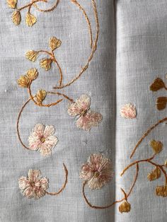 an embroidered fabric with flowers and leaves on the side, as well as gold thread