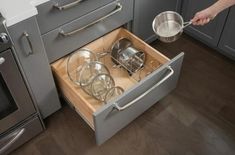 an open drawer in the middle of a kitchen with pots and pans on it