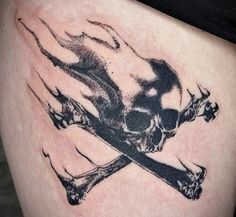 a skull and crossbone tattoo on the thigh