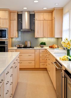 a large kitchen with wooden cabinets and stainless steel appliances, along with white counter tops