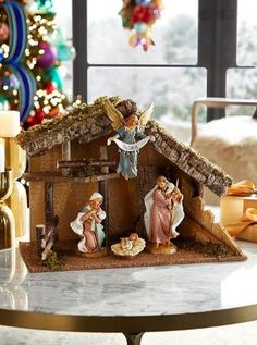 a nativity scene is displayed on a table in front of a decorated christmas tree