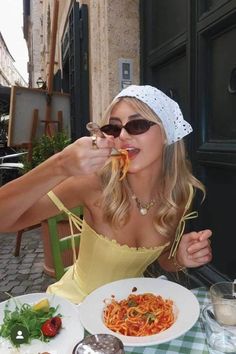 a woman sitting at a table eating spaghetti