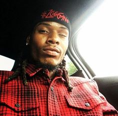 a man with dreadlocks sitting in the back seat of a car wearing a red and black plaid shirt