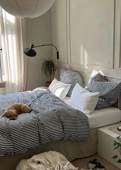 a dog laying on top of a bed in a room with white walls and windows