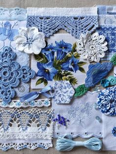 many different pieces of lace and flowers are laid out on a tablecloth with blue trimmings