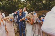 a group of people standing around each other holding up cups with water in them and drinking