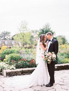 a bride and groom standing in front of some flowers at the end of their wedding day