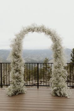 A oval wedding arch completely covered with babies breath flowers sits on a wooden deck with the mountains in the background. Babies Breath Arch, Wedding Aisle Decorations Outdoor, Floral Arch Wedding, Provence Wedding, Cottage Wedding, Outdoor Fall Wedding